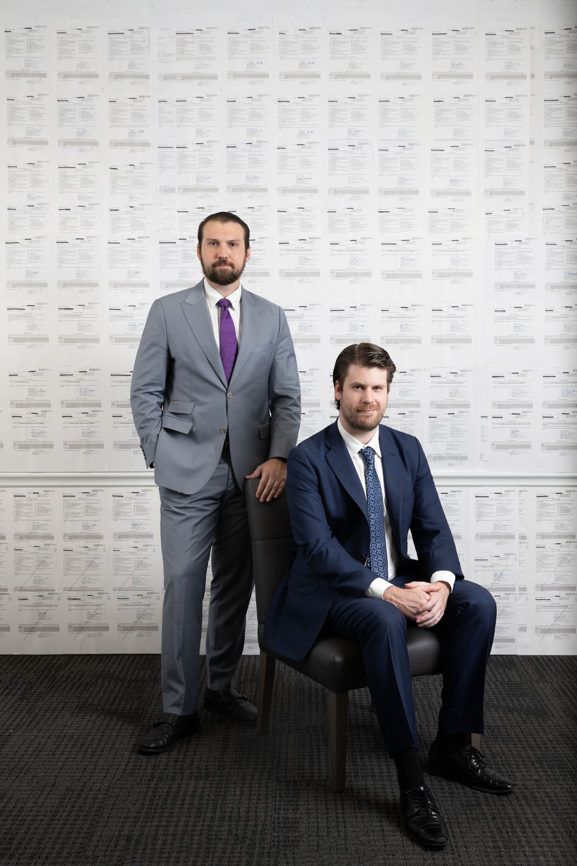 Two attorneys standing in front of a wall, with their arms crossed