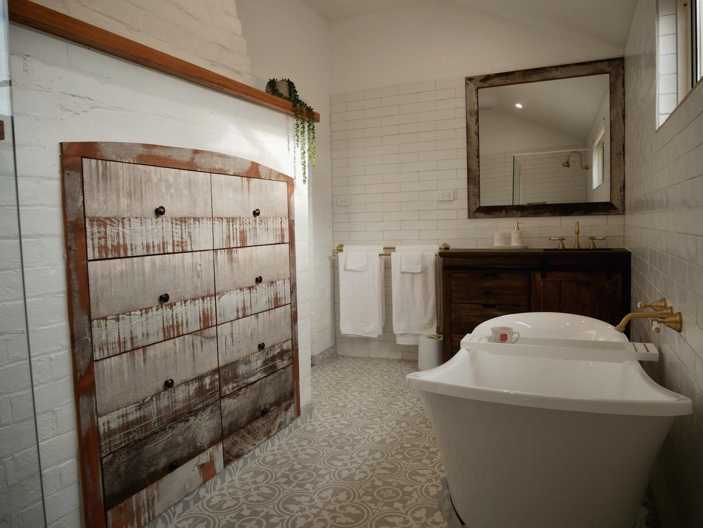 Bathroom with a vintage-style bathtub, rustic wooden accents, and white brick walls.