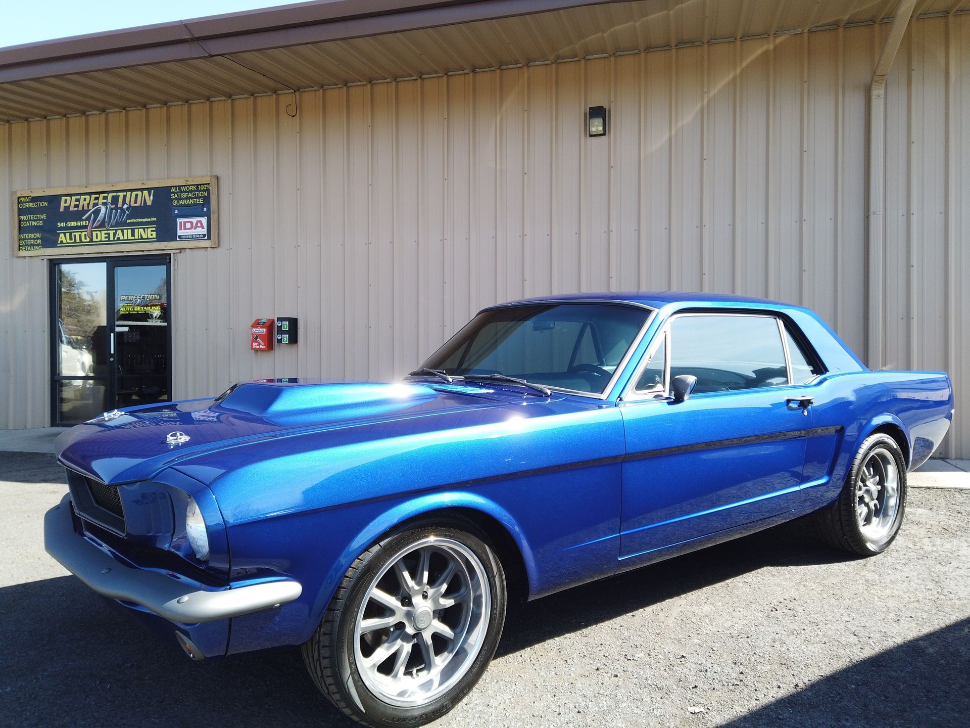 A blue mustang is parked in front of a building