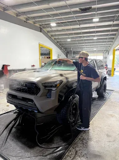 Person using pressure washer to do car wash service.