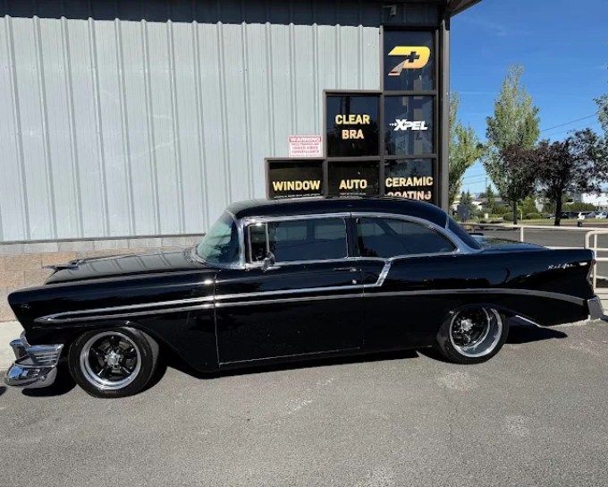 Classic black Chevrolet with custom tint darkness, parked outside Perfection Plus Auto Salon shop