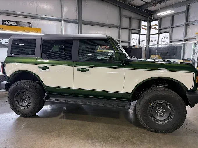 Green-and-white SUV indoors with PPF, highlighting protected finish.