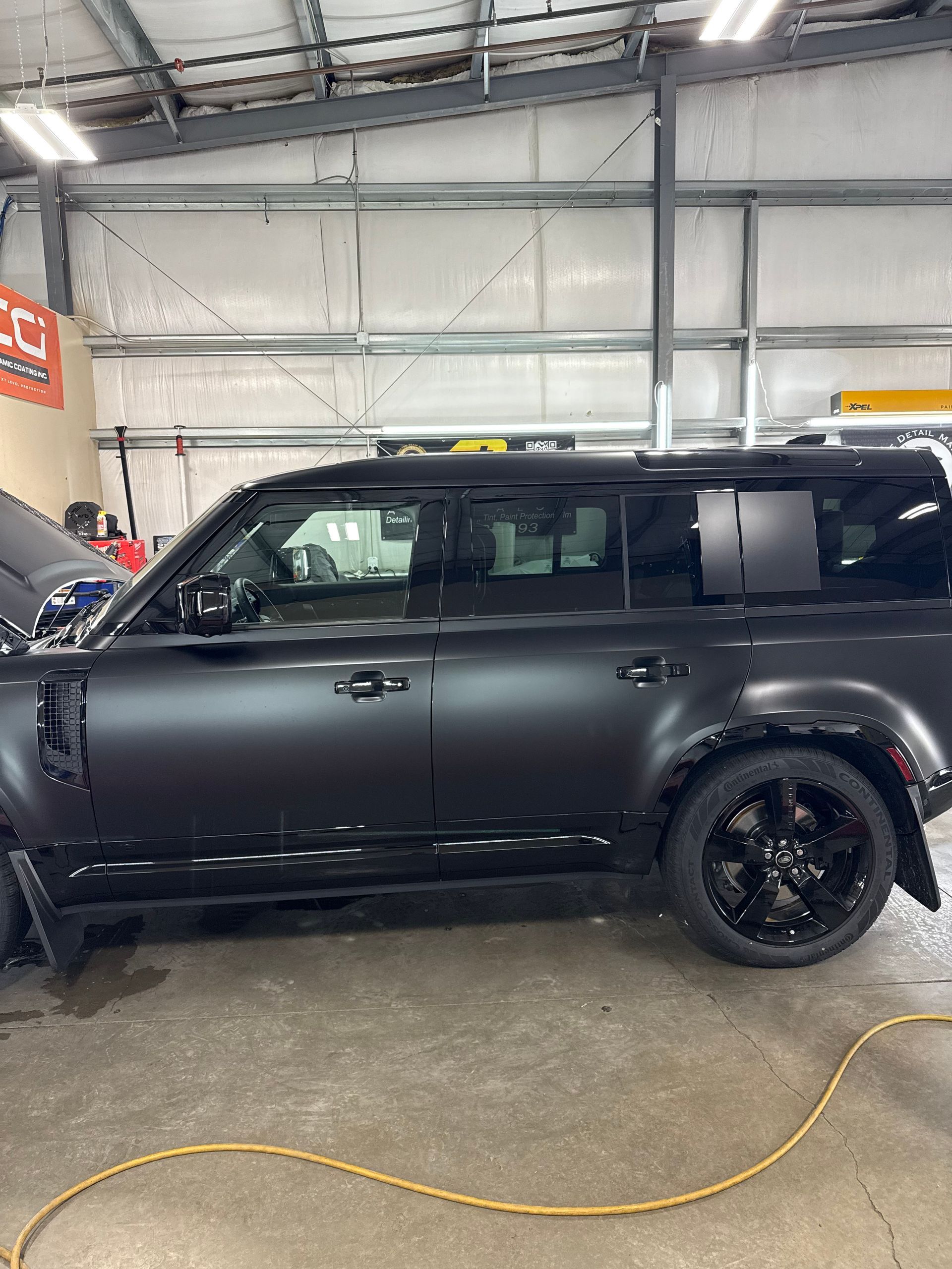 A black suv is parked in a garage with the hood open.