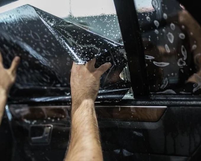 Technician applying tinted windows film to truck door at Perfection Plus Auto Salon