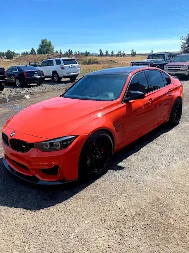Red BMW with ceramic coating, parked outdoors, shining despite rain and moisture.