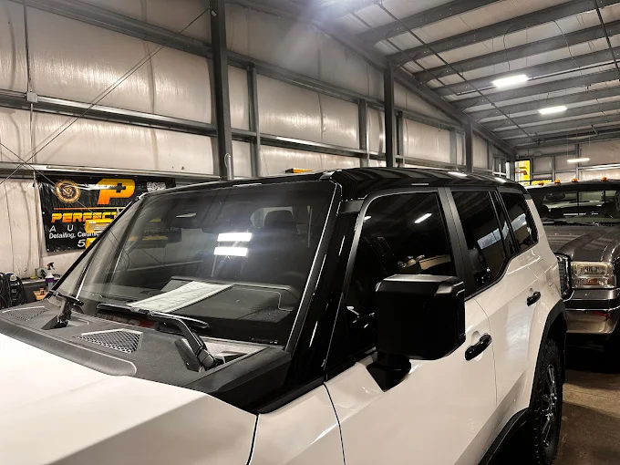 Black-and-white SUV parked inside a warehouse garage with another vehicle behind it