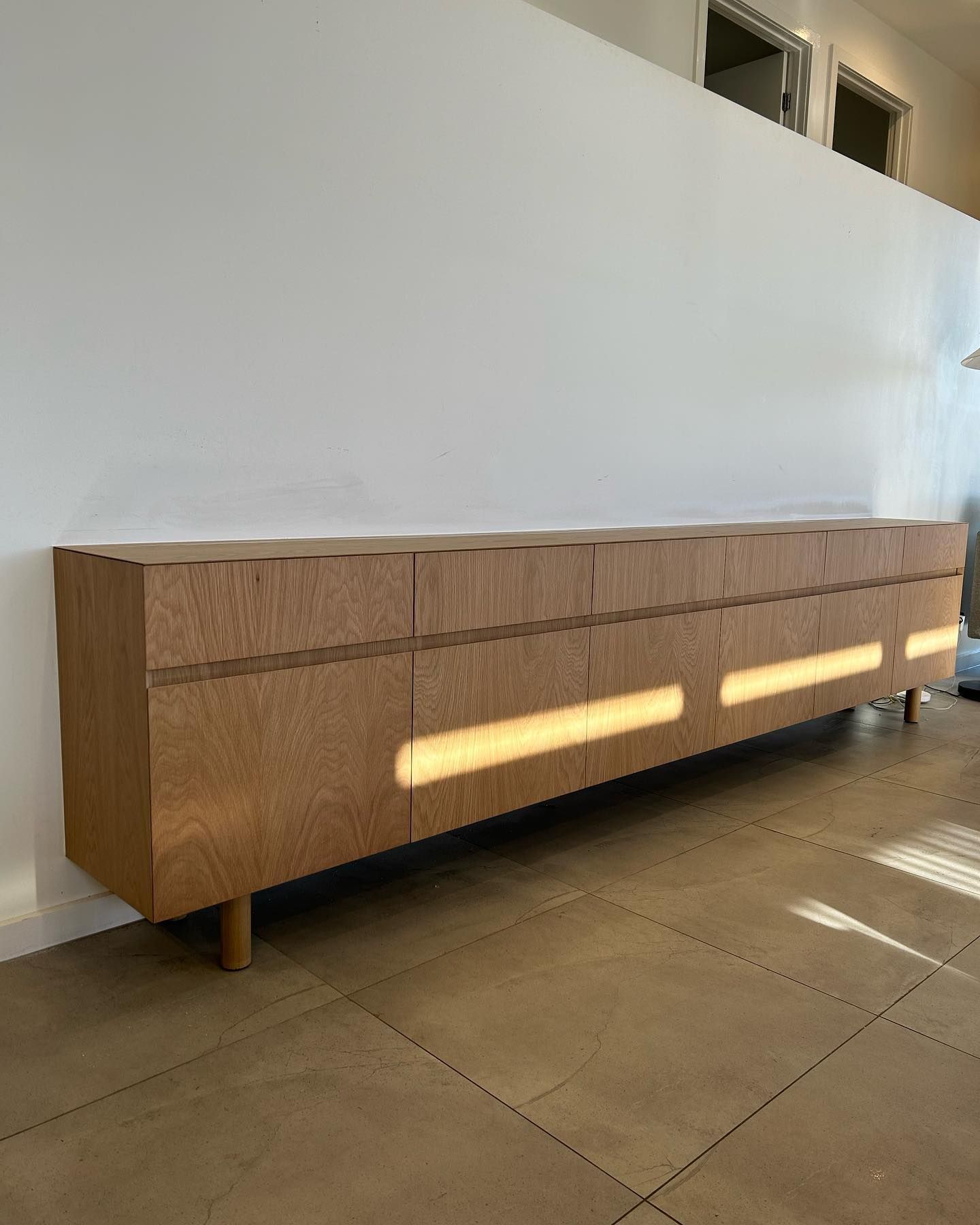 A Long Wooden Cabinet is Sitting in a Living Room Next to a Wall — Precision Kitchens & Cabinets in Ballina, NSW