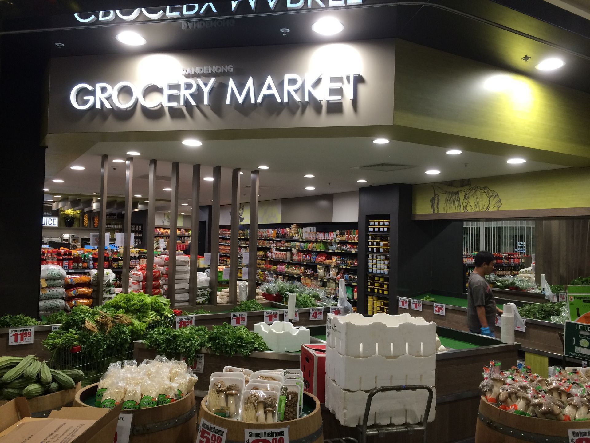 Grocery market entrance with bright sign, flower displays, and stocked shelves inside