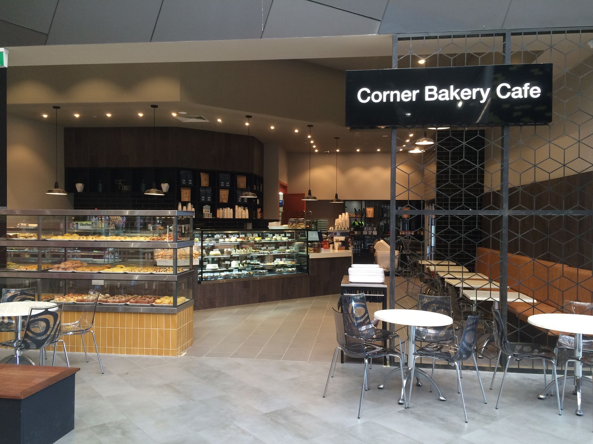 Corner Bakery Cafe storefront with glass display cases and empty tables and chairs inside a mall.
