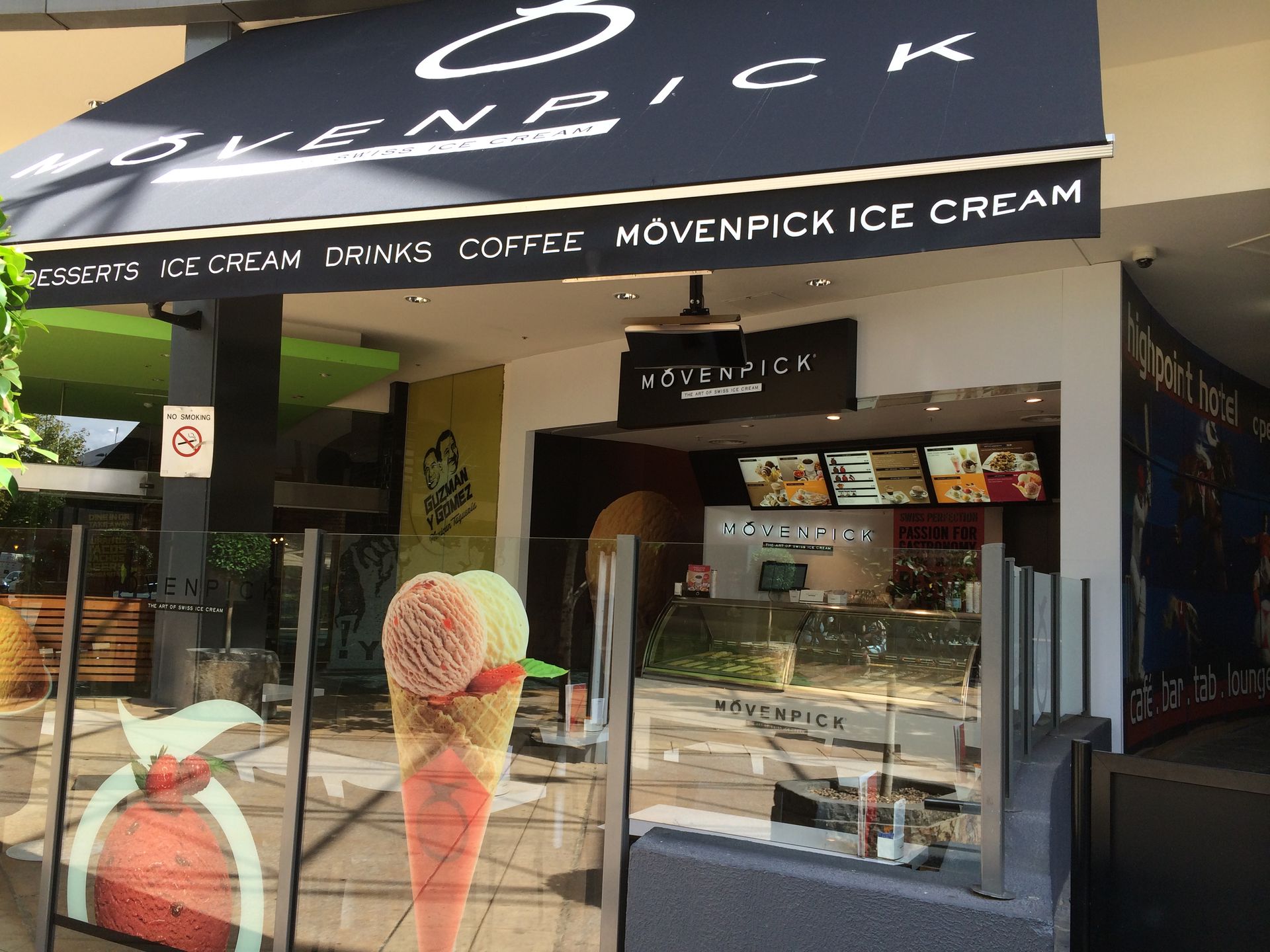 Ice cream shop storefront with black awning, colorful ice cream cone graphics, and display case inside