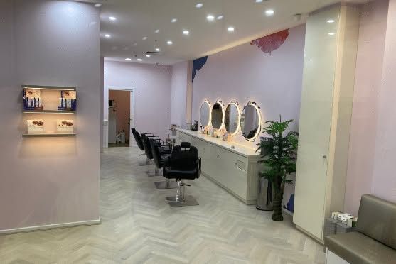 Modern salon interior with styling chairs, illuminated mirrors, and pastel pink walls