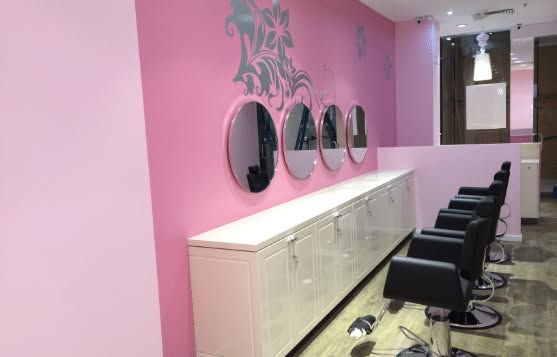 Pink salon interior with styling chairs, mirrors, and a long counter against the wall
