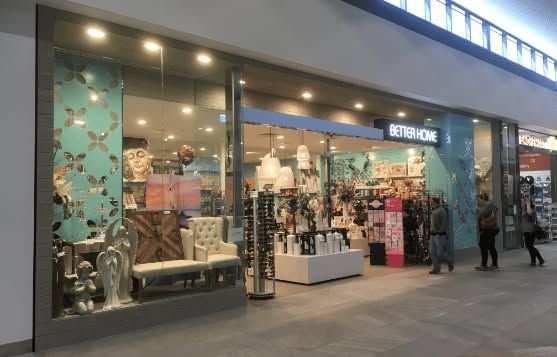 Exterior of a stylish boutique storefront with mannequins, handbags, and floral teal decor