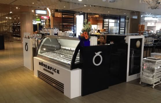 Counter with pastries and a black sign in a shopping mall café kiosk