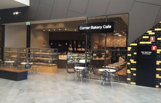 Corner Bakery Cafe storefront in a mall, with empty tables and glass display cases