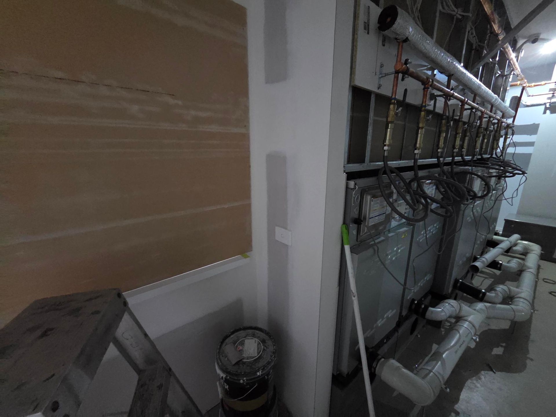 Utility room with pipes, wiring, and HVAC equipment along a wall.