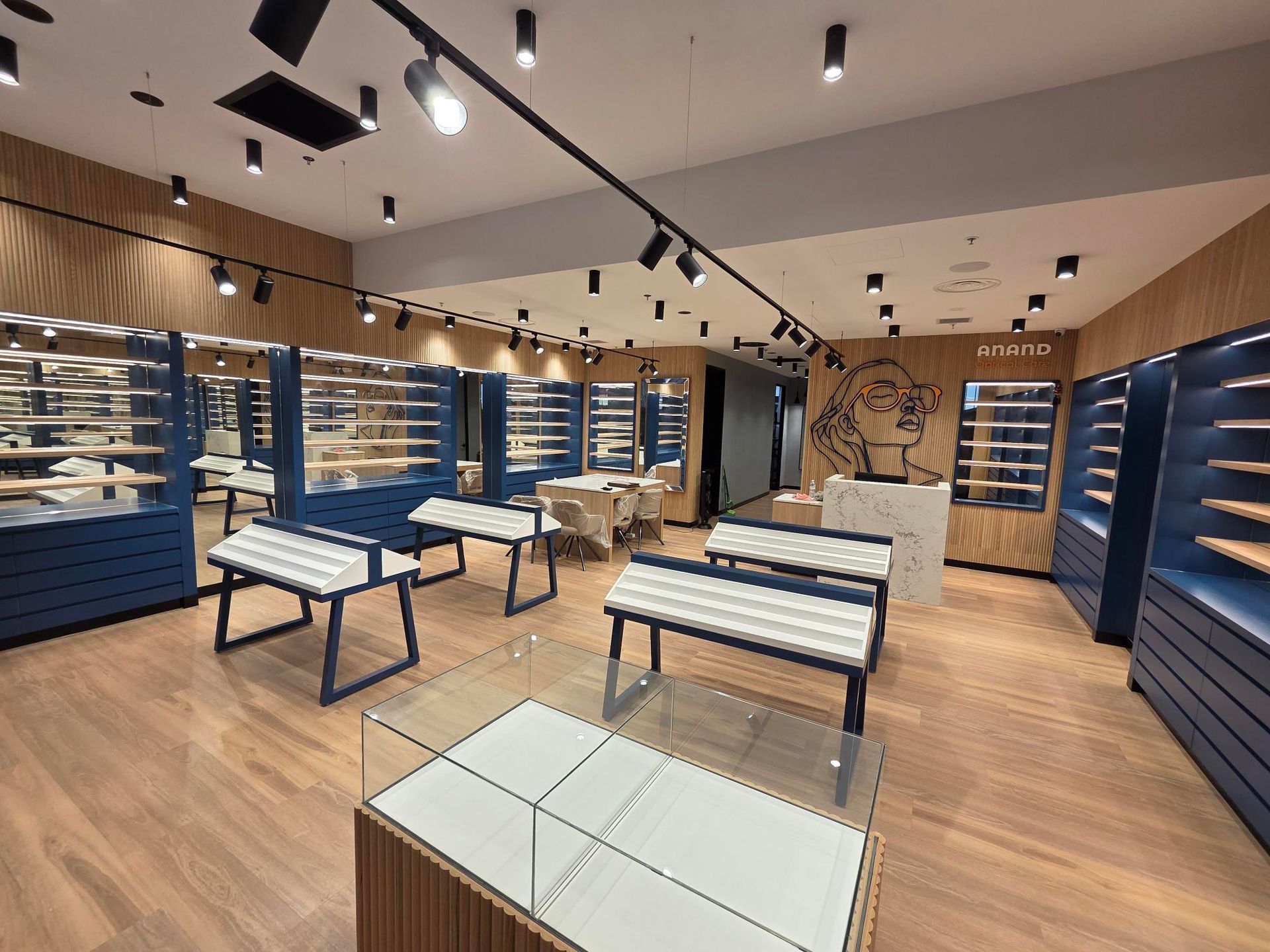 Empty modern retail showroom with blue shelving and wooden floors under ceiling track lights