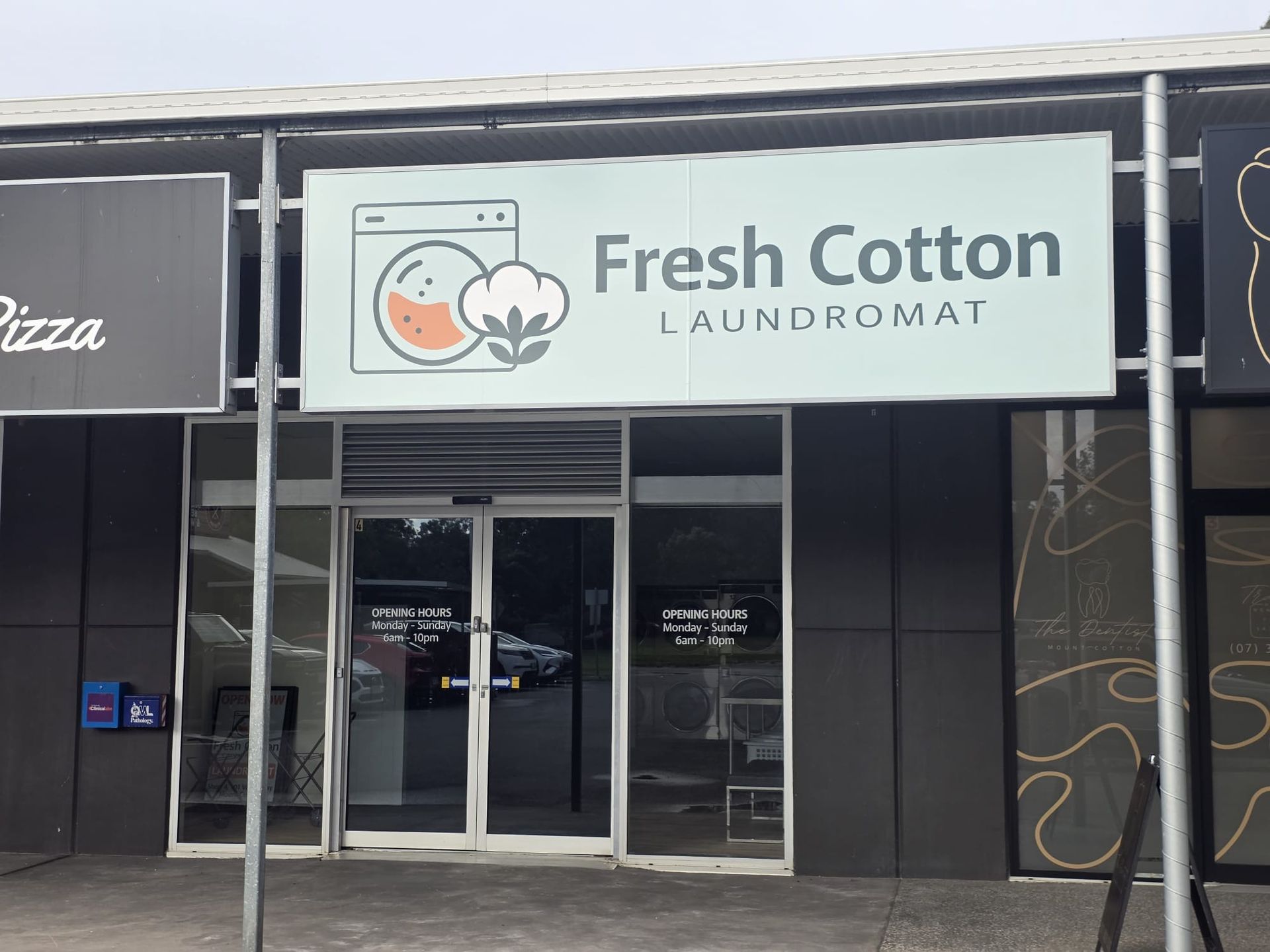 Storefront for Fresh Cotton Laundromat with glass doors and a light blue sign above the entrance