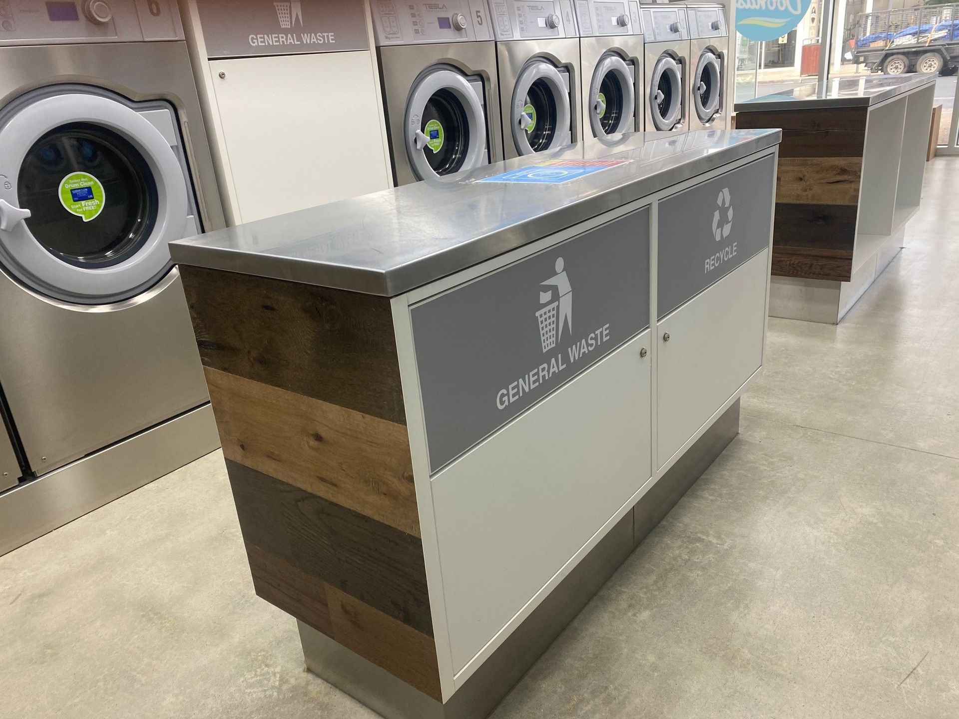 Laundry room with rows of washing machines and a central sorting counter on a polished floor