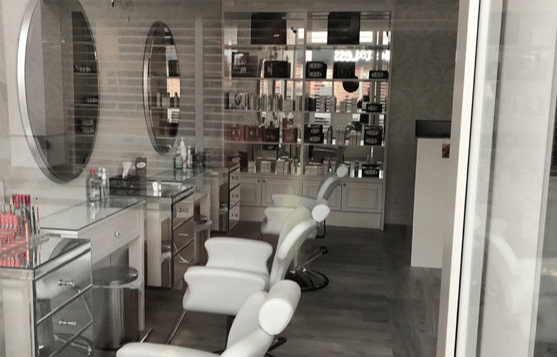 Modern salon interior with white styling chairs, mirrors, and product shelves