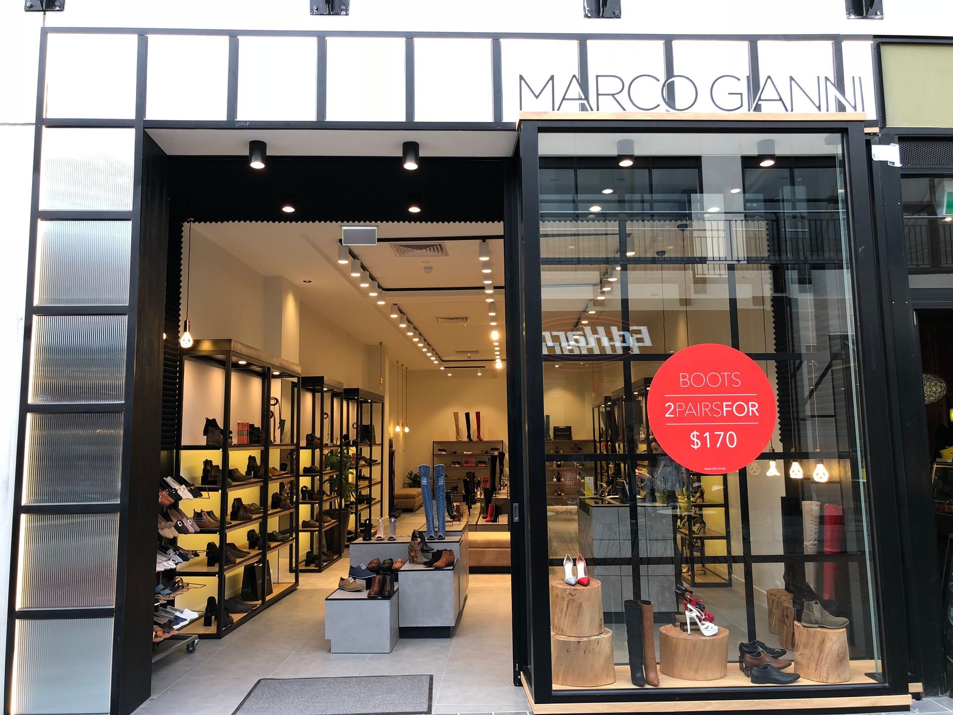 Marco Gianni boutique storefront with black-framed glass windows and sale sign inside