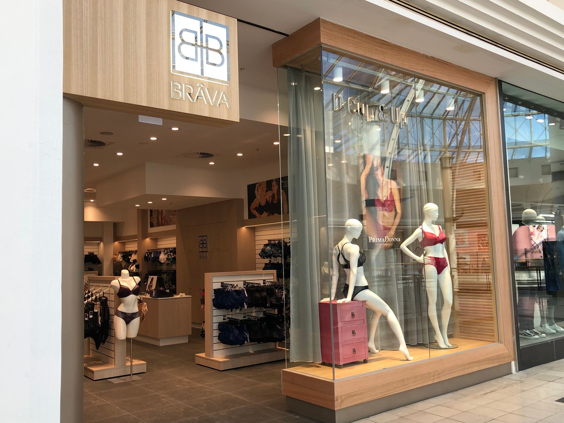 Storefront display with mannequins in a lingerie shop window and open entrance inside a mall.