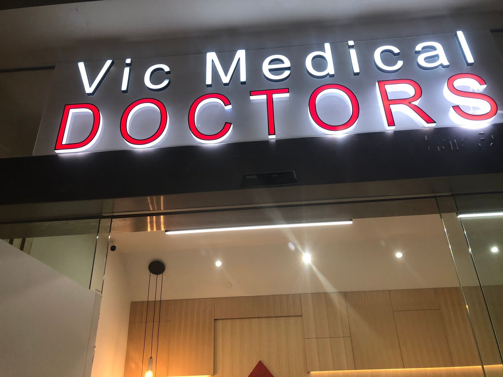 Vic Medical Doctors sign above a glass storefront at night