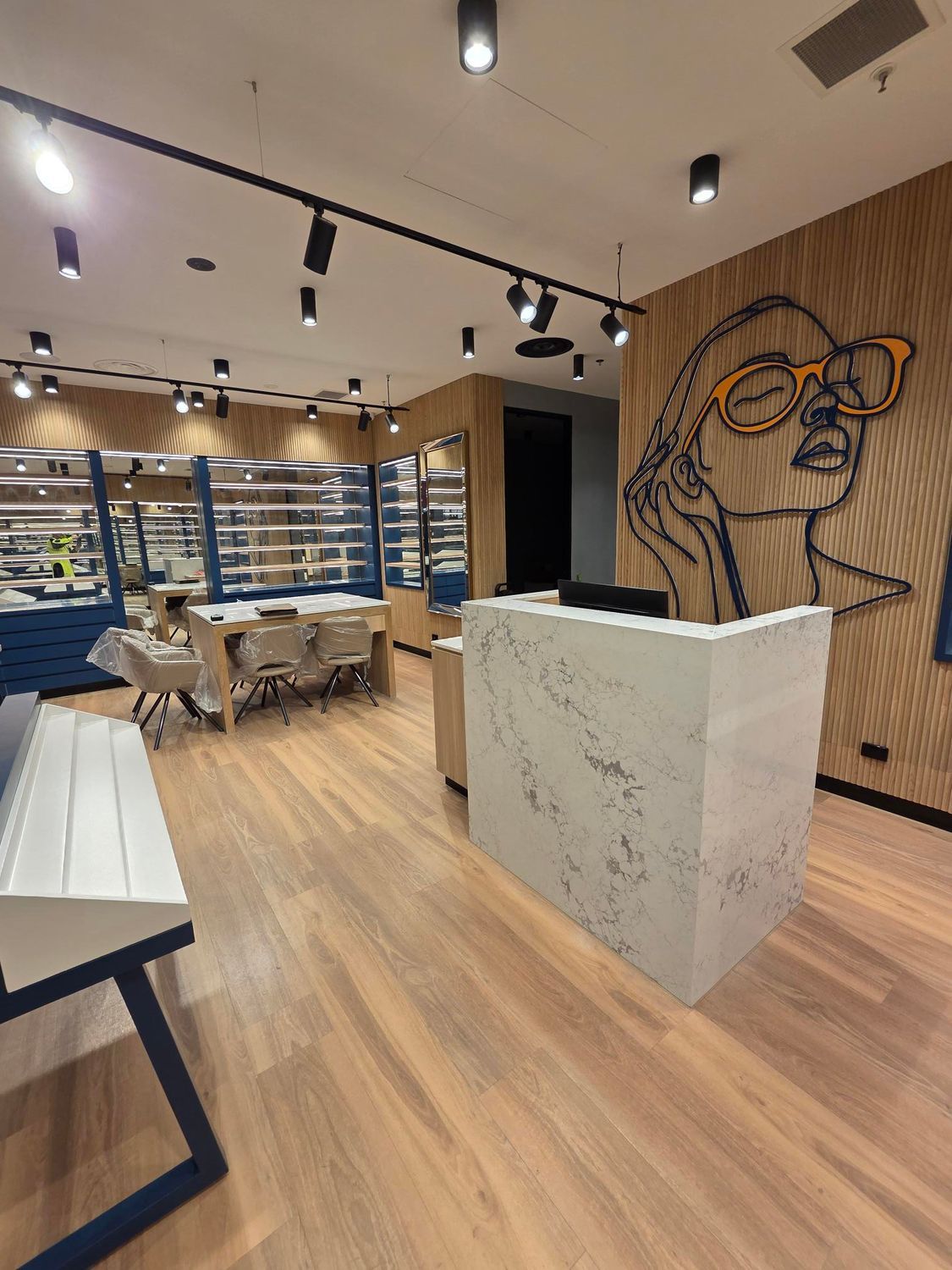 Modern cafe interior with wood flooring, white counter, tables, chairs, and mural on the wall