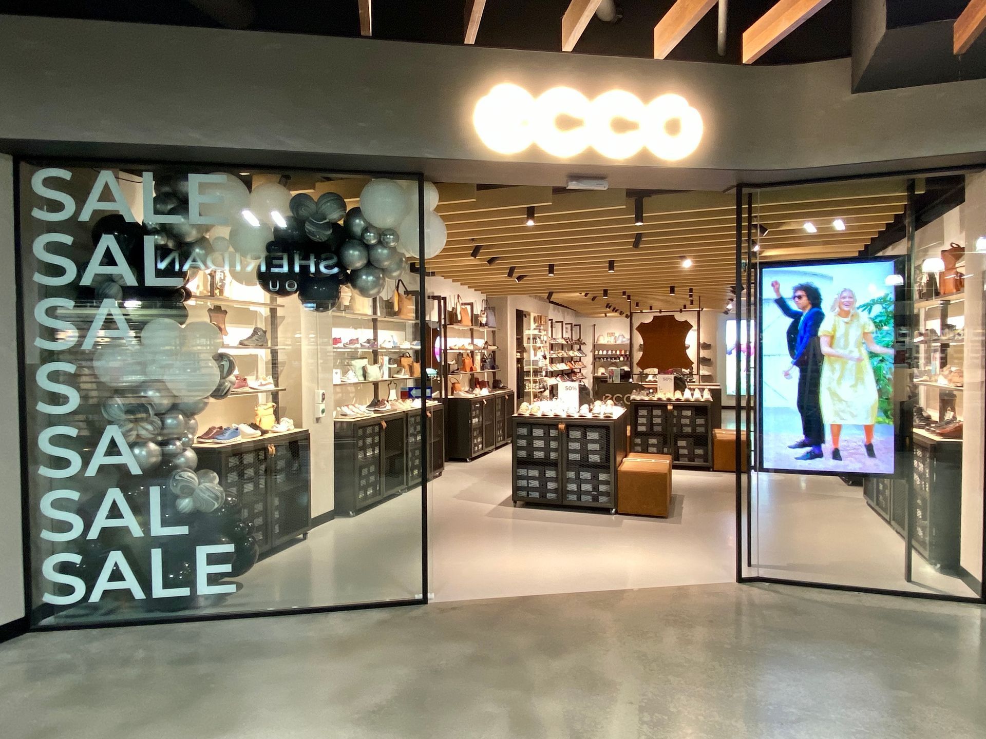 Storefront with SALE signs, open entrance, and bright interior displays.