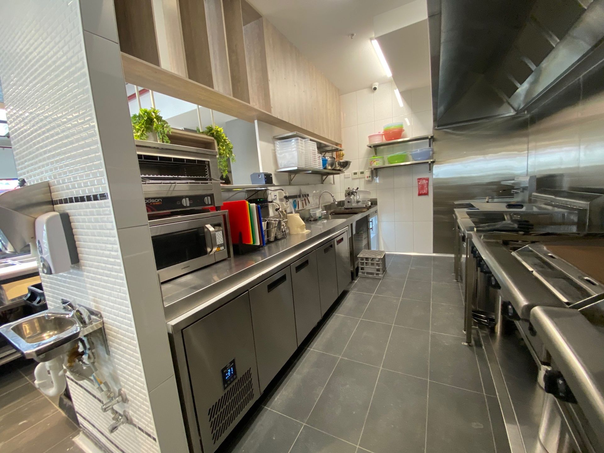Modern commercial kitchen with stainless steel counters, ovens, and dark tile floor