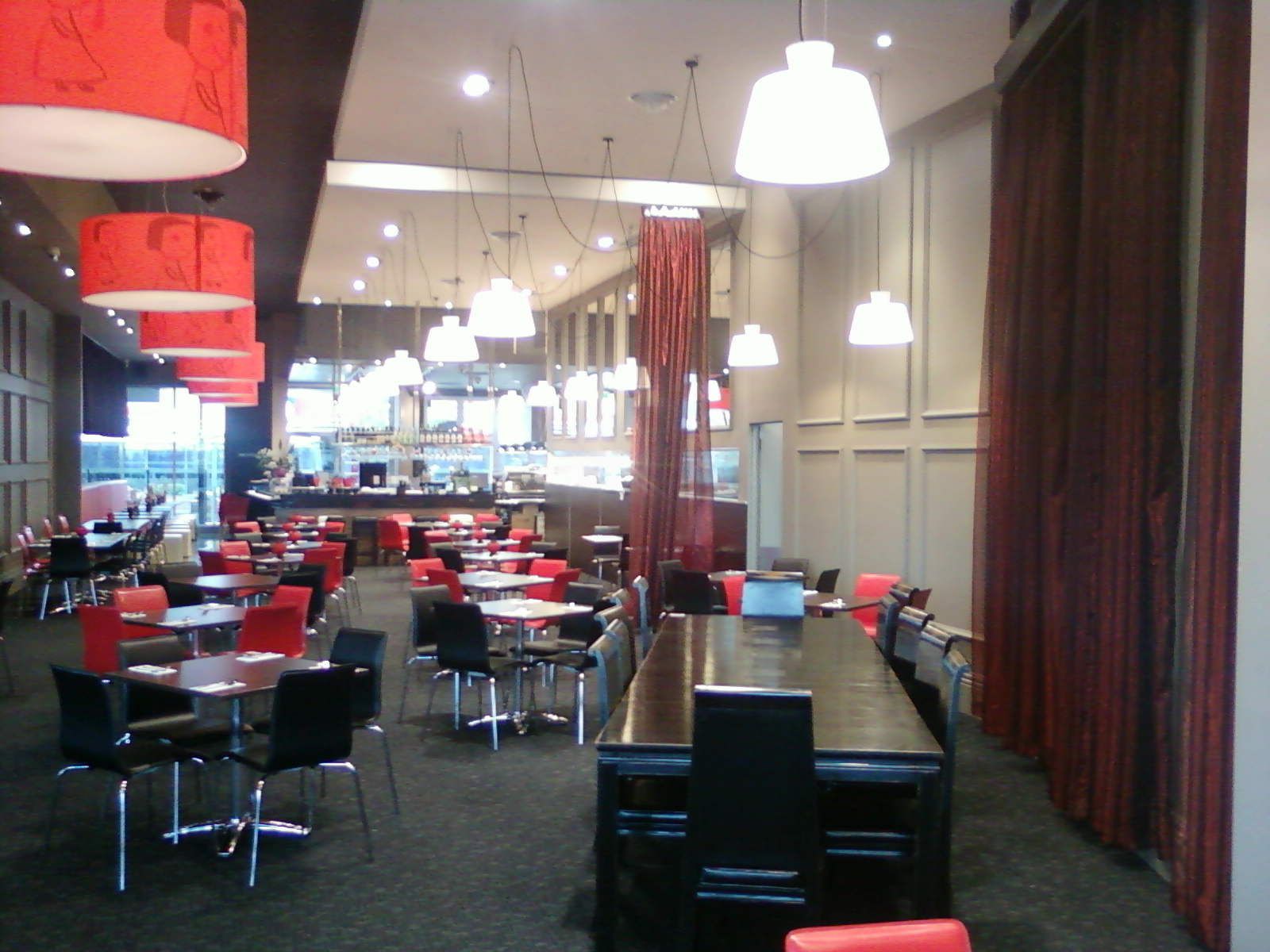 Modern restaurant dining room with red and black chairs, tables, and hanging pendant lights