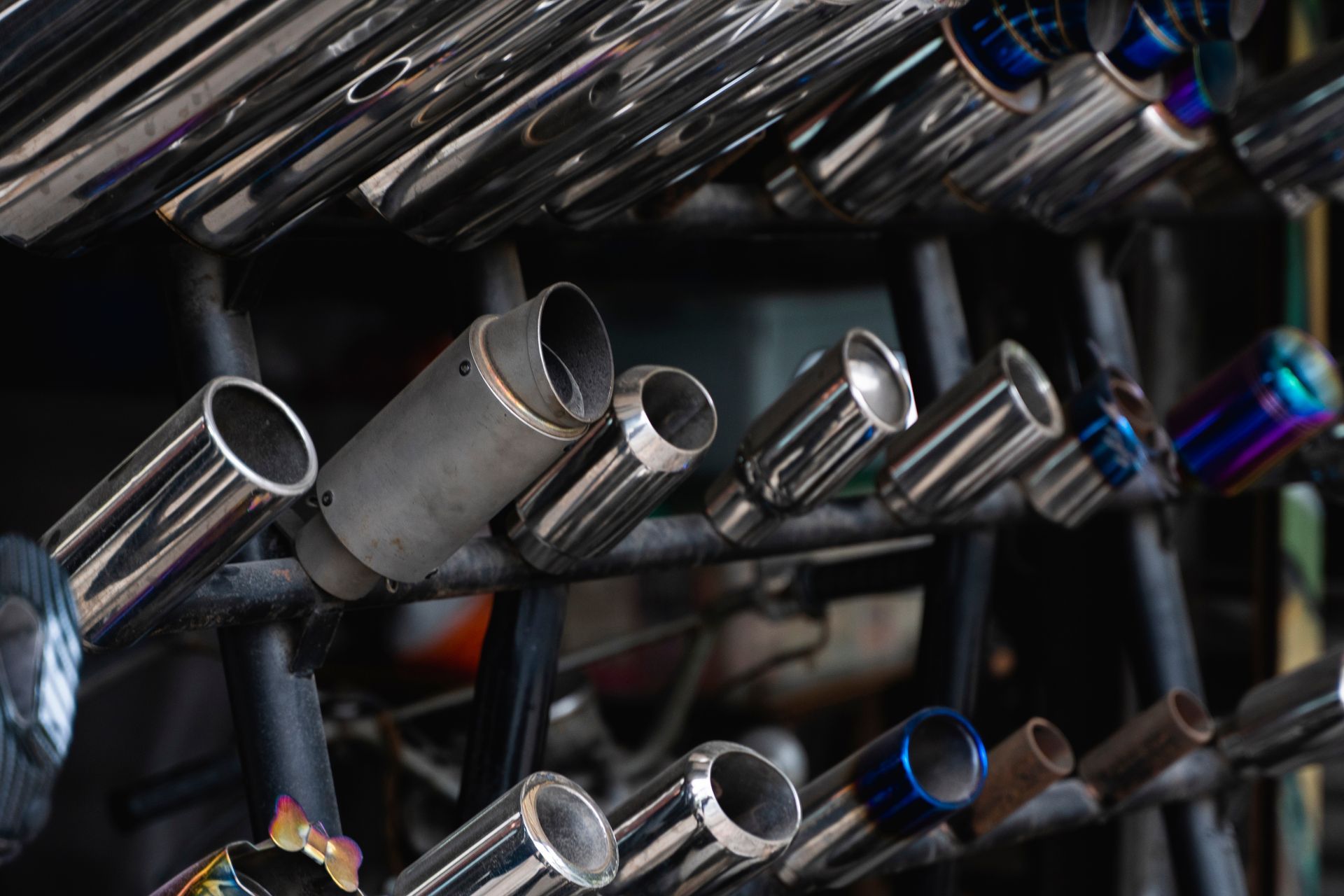 Multiple shiny metal exhaust pipes arranged on a rack. Multiple shiny metal exhaust pipes arranged on a rack.