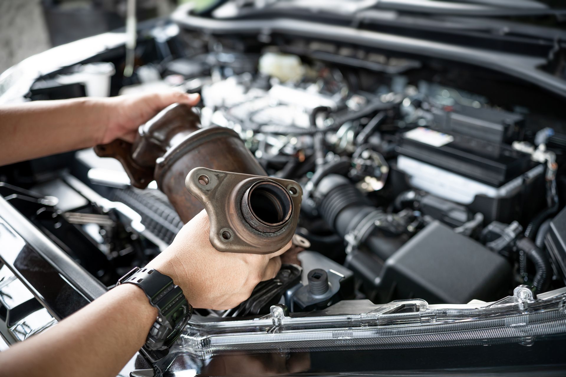 Mechanic holding a removed catalytic converter during an exhaust system inspection