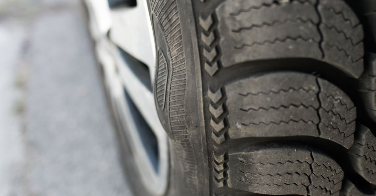 A tire sidewall with a raised oval bulge beside deep tread and a blurred wheel.
