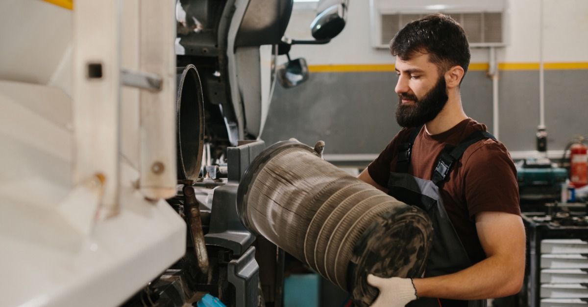 A mechanic replaces a dirty air filter from a truck parked in a repair shop.