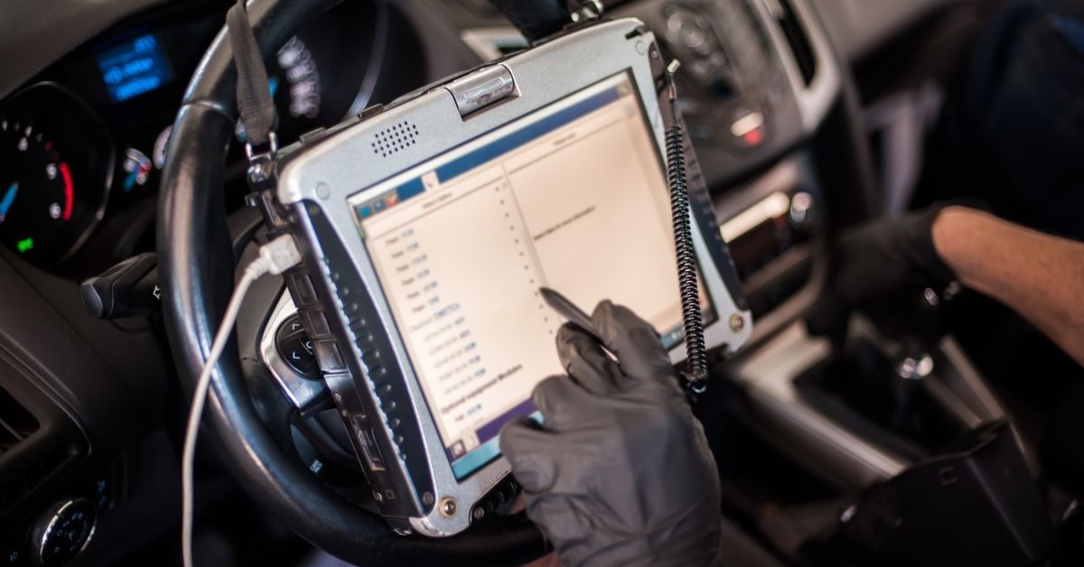 A hand using a tablet mounted on a steering wheel while running diagnostics.
