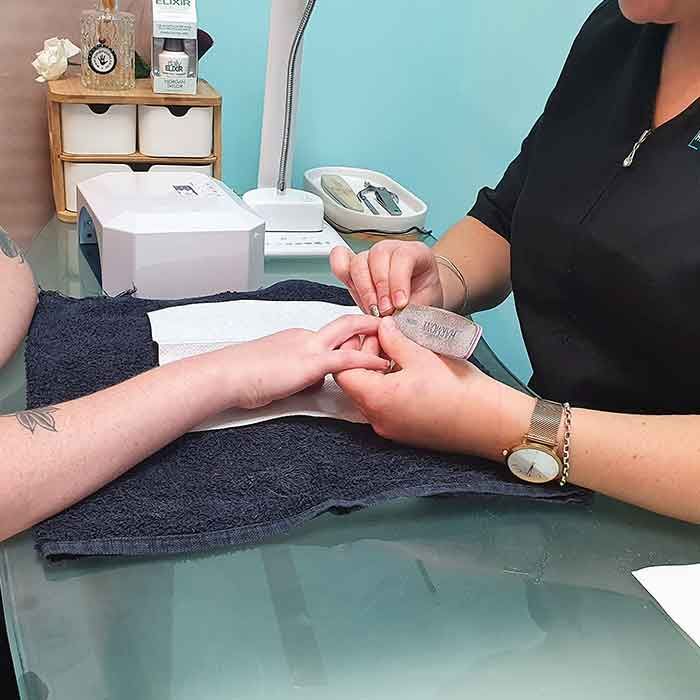 A woman is giving a manicure to another woman