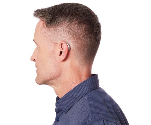 Man with a hearing aid behind the ear, wearing a blue button-down shirt.