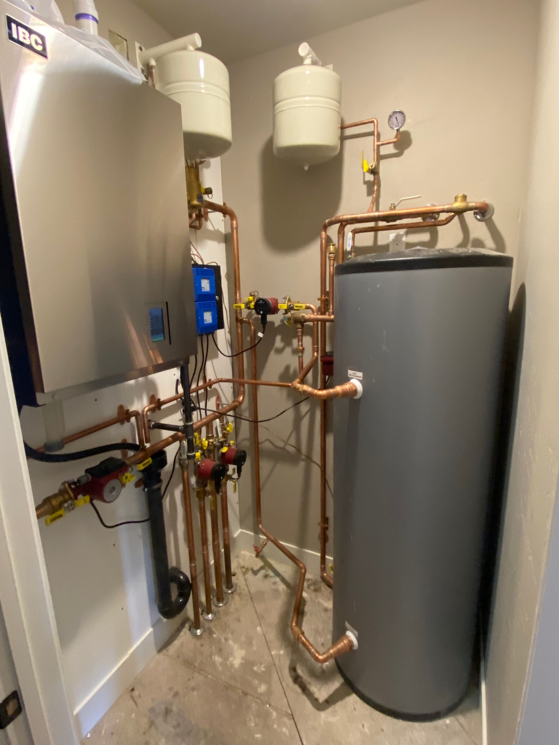Home water heater and plumbing system with two white expansion tanks and a large gray storage tank.