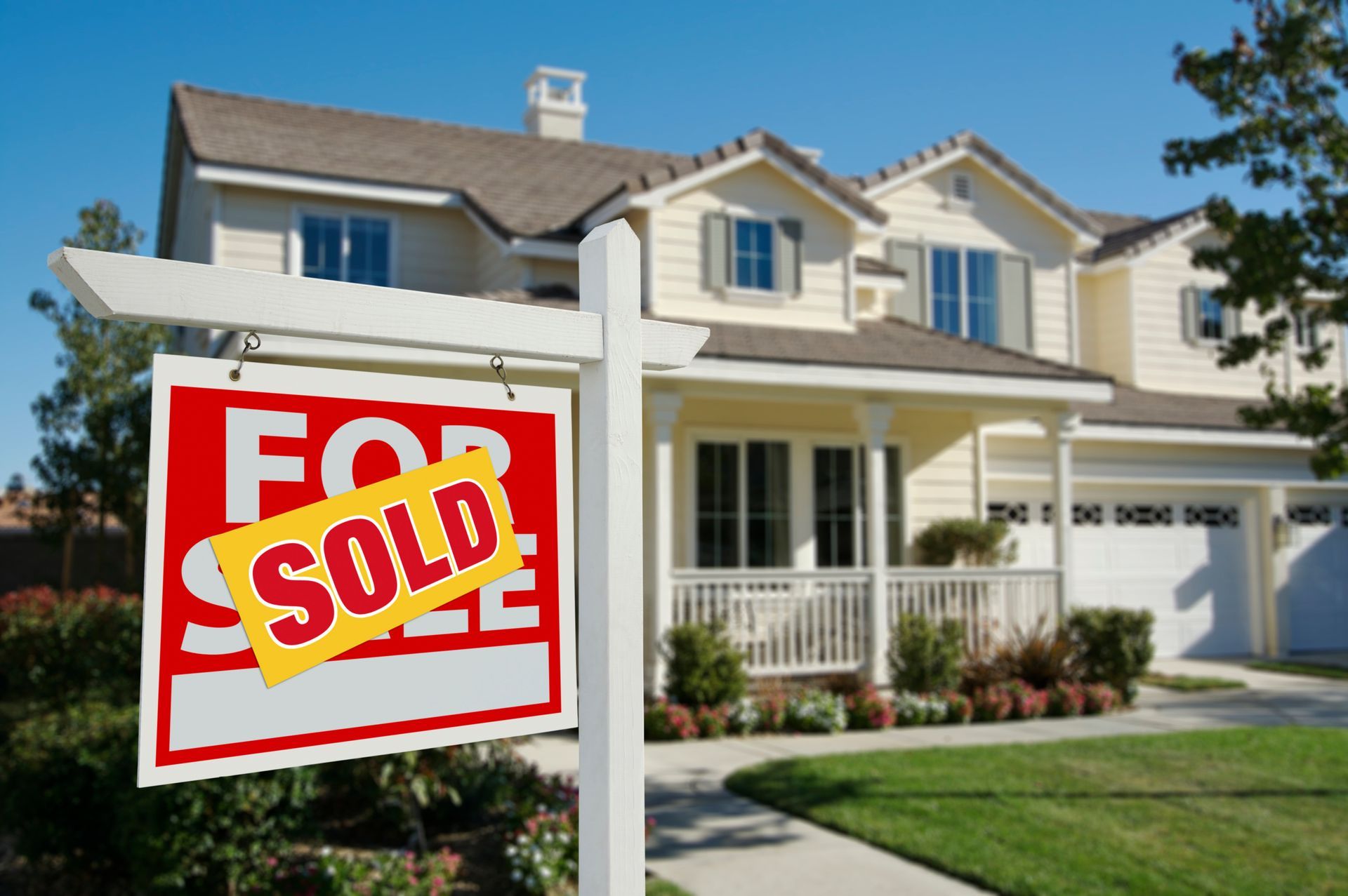 A beige two-story house with a lawn, featuring a A beige two-story house with a lawn, featuring a