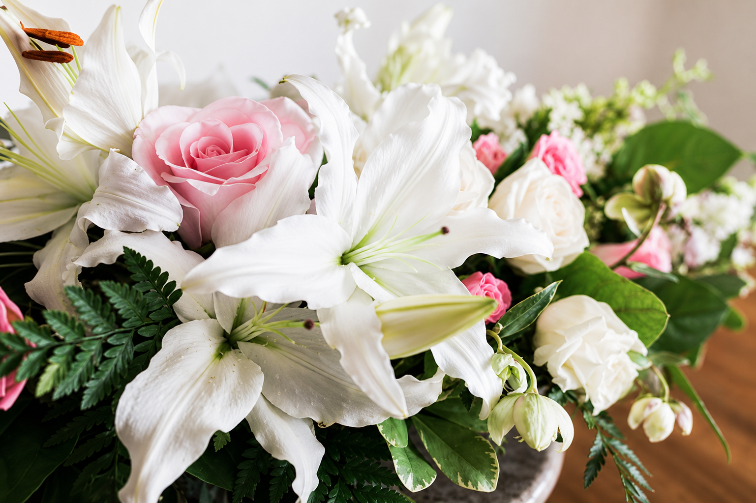 Rose rosa e gigli bianchi disposti con verde in un bouquet floreale