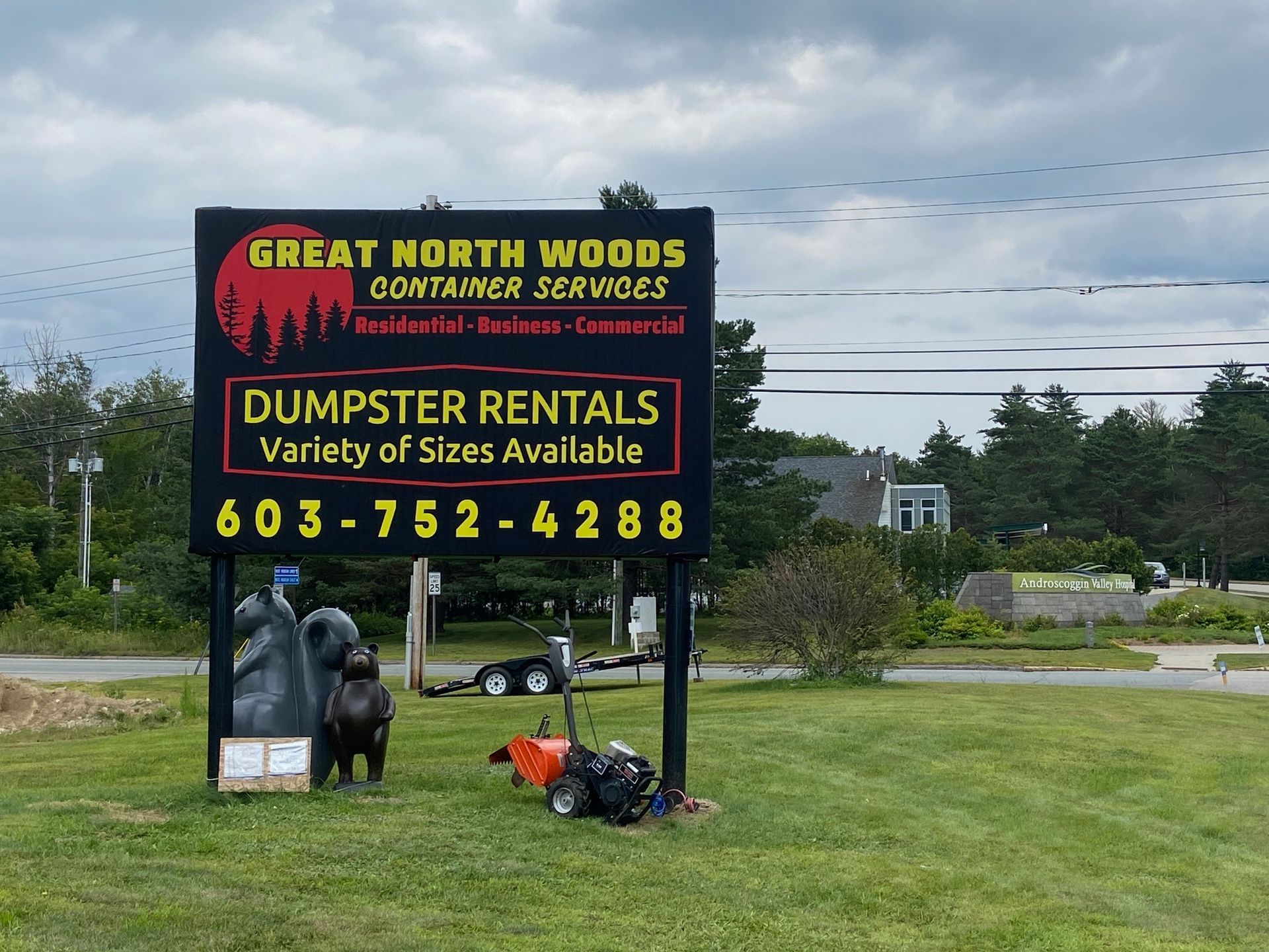 Sign for Great North Woods Container Services with dumpster rentals, phone number, and bear statues.
