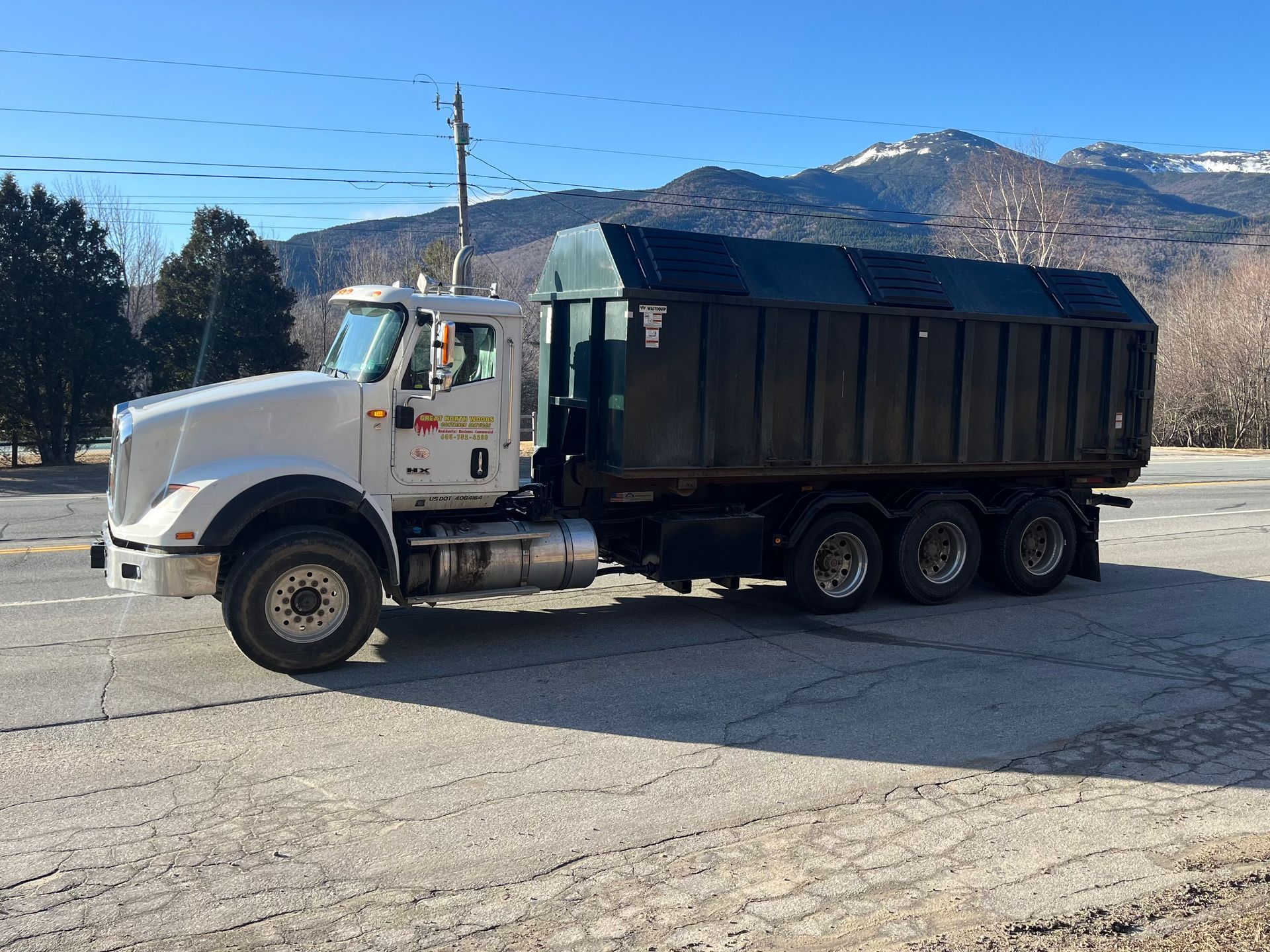 White dump truck on asphalt with mountains in background.