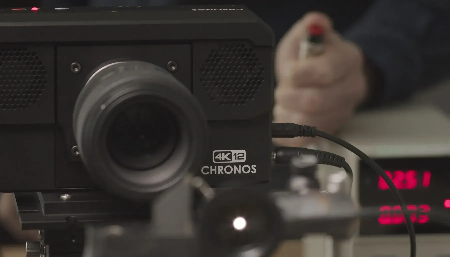 A person is holding a red marker in front of a 4k projector.