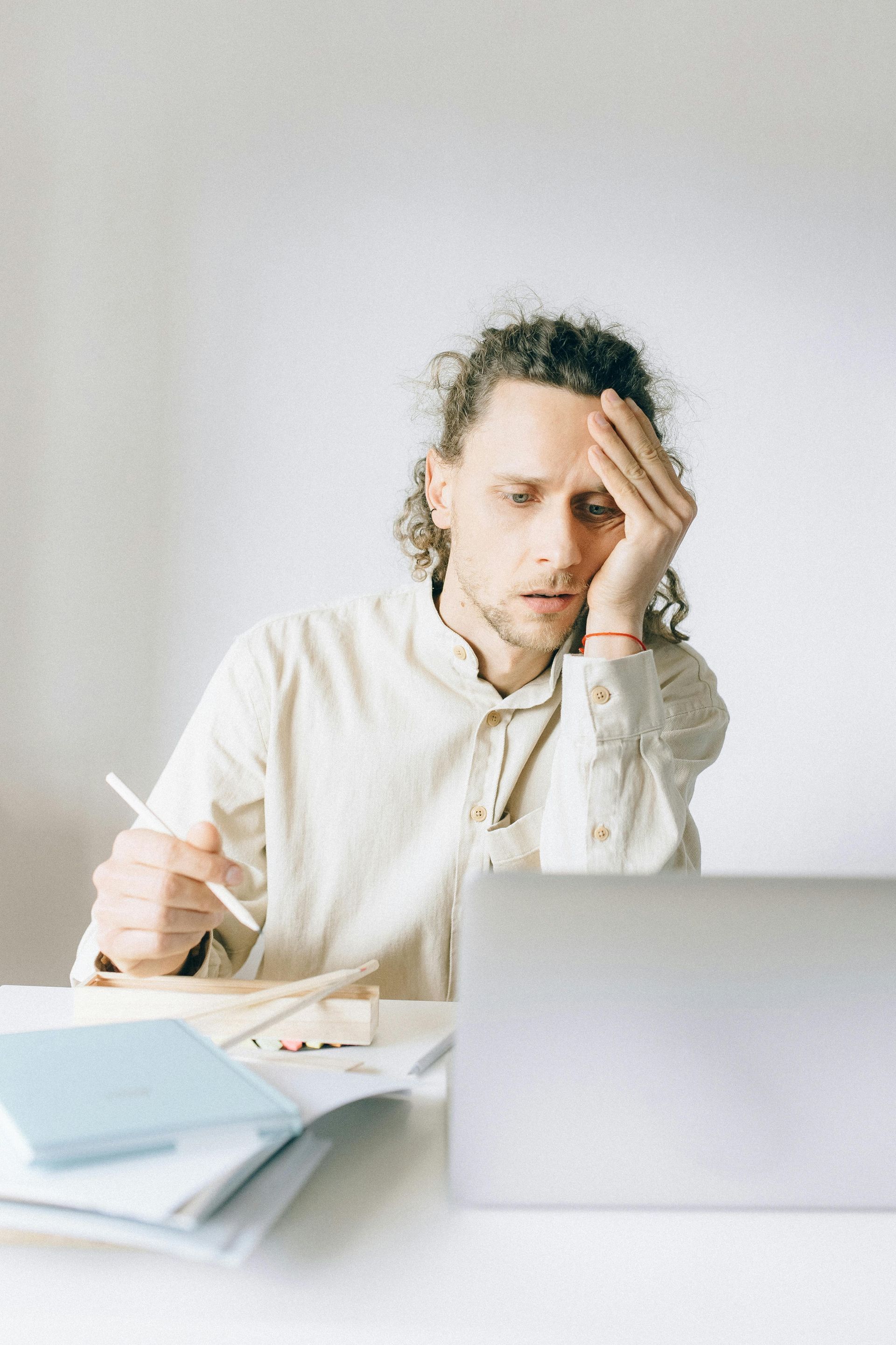 A man is sitting at a desk in front of a laptop computer.