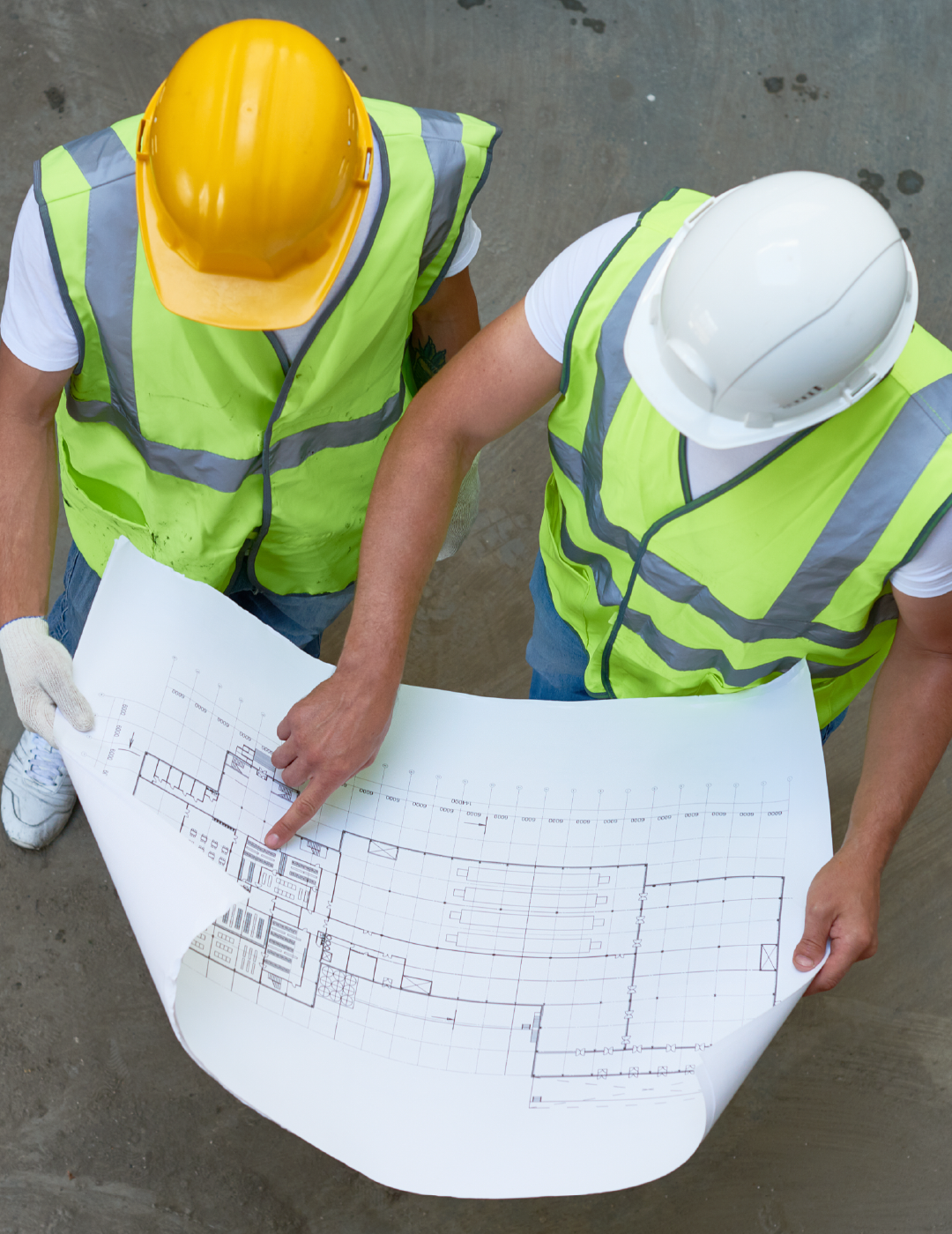 Two construction workers are looking at a blueprint together