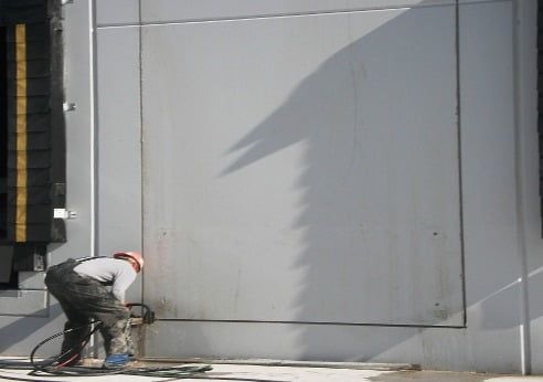A man wearing a hard hat is working on a wall
