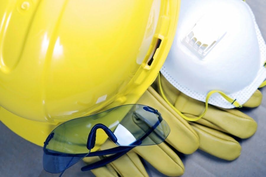 A yellow hard hat a pair of safety glasses and gloves