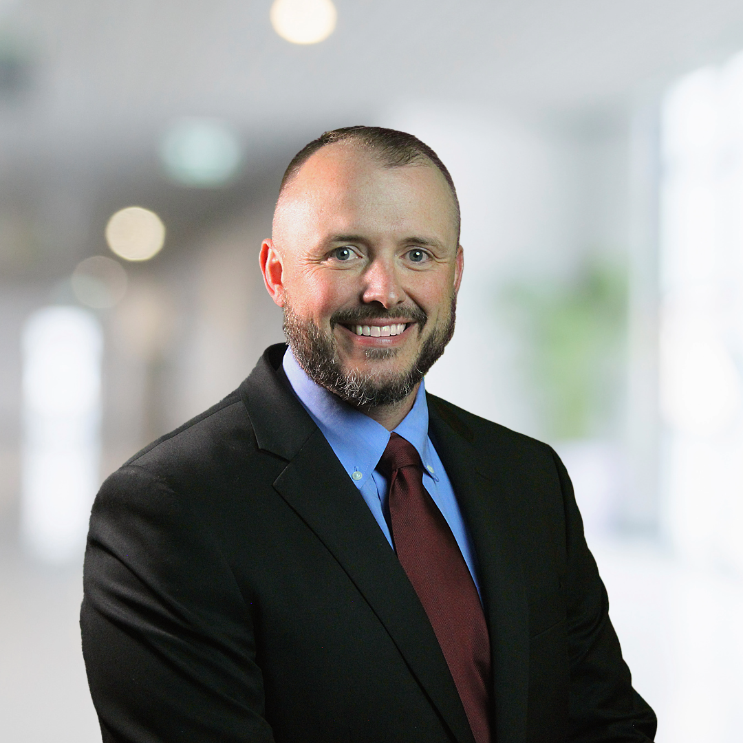 A man in a suit and tie is smiling for the camera