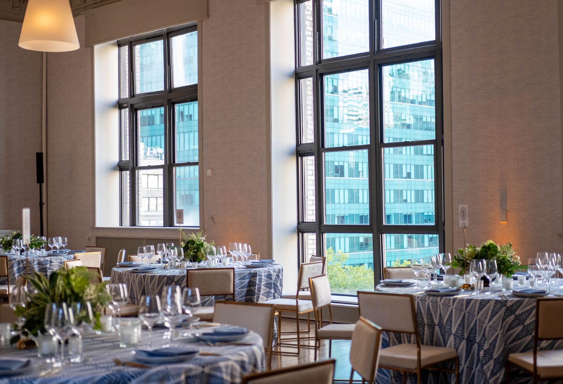 Elegant restaurant dining room with set tables, large windows, and city views